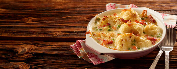 Canvas Print - Top studio shot of a palatable baked cauliflower with cheese in a bowl placed on a wooden table