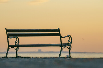 Wooden bench on a lakeshore on a sunset sky background