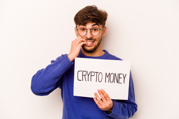 Wall Mural - Young hispanic man holding a crypto money placard isolated on white background biting fingernails, nervous and very anxious.