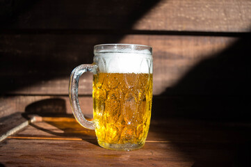 Poster - Glass of beer on a wooden background with shadows