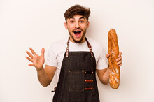 Young Baker Hispanic Man Isolated On White Background Receiving A Pleasant Surprise, Excited And Raising Hands.