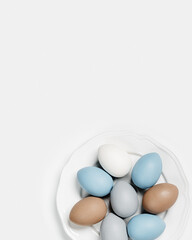 Wall Mural - Painted Easter eggs blue, gray, beige colored on round white plate, light background with copy space. Chicken egg pastel shades. Easter holiday food, simple minimal design aesthetic flat lay