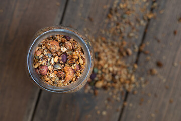 Wall Mural - Top view of a glass jar with nuts and granola on the wooden table