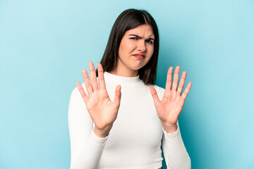 Wall Mural - Young caucasian woman isolated on blue background rejecting someone showing a gesture of disgust.