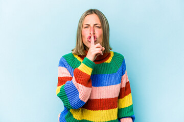 Wall Mural - Young caucasian woman isolated on blue background keeping a secret or asking for silence.