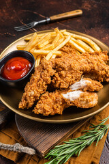 Wall Mural - Fried Breaded chicken tender strips with french fries and tomato ketchup on a plate. Dark backgrund. Top view