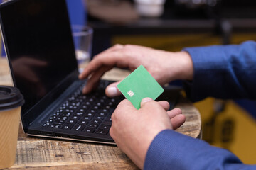 Man's hand using credit card along with his laptop