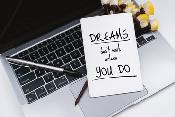 Wall Mural - White Paper on Laptop With Inspirational Quote . Dreams Don't Work Unless You Do.
