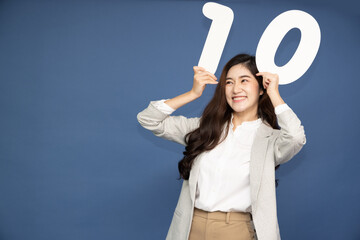 Wall Mural - Young Asian business woman showing number 10 or ten isolated on deep blue background