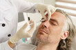 © blackday - Female doctor making marks on client's face before filler injection