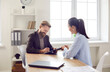 © Studio Romantic - Happy client signing some paper documents. Smiling bearded man in suit sitting at office desk with female bank manager, business assistant, or insurance agency worker and putting signature on contract