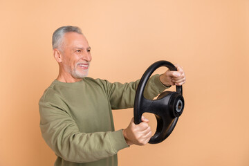 Poster - Photo of funny elder white hairdo man drive car wear grey shirt isolated on beige color background