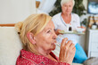 Kranke Seniorin nimmt Medikamente ein mit Glas Wasser