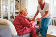 Frau vom Pflegedienst hilft alter Frau beim Aufstehen