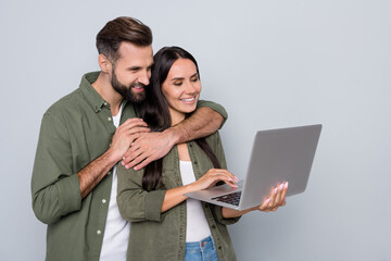 Aufkleber - Portrait of attractive tender cheerful couple using laptop watching video isolated over grey pastel color background