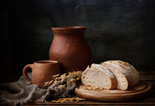 Homemade Bread And Vintage Ceramic Kitchenware On An Old Wooden Table. Artistic Still Life In Vintage Style.