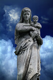 Fototapeta  - Queen of Heaven. Virgin Mary with baby Jesus Christ. An ancient statue against blue sky background.