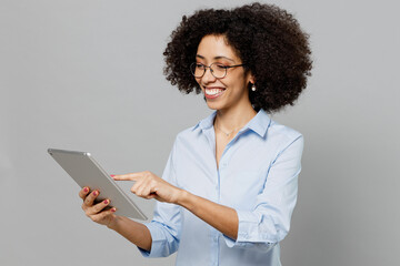Wall Mural - Young smiling happy employee business corporate lawyer woman of African American ethnicity in classic formal shirt work in office hold use tablet pc computer isolated on grey color background studio.