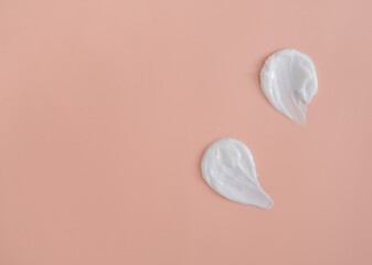 Wall Mural - White smear of cosmetic cream on a beige background. Creamy foundation texture isolated. Smear of face cream. Close up of cream texture