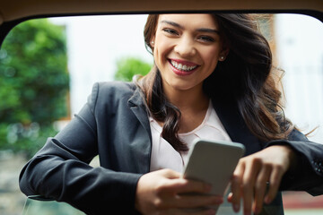 Wall Mural - I always plan my day before I get going. Shot of an attractive young businesswoman using a cellphone leaning on the window of a car.