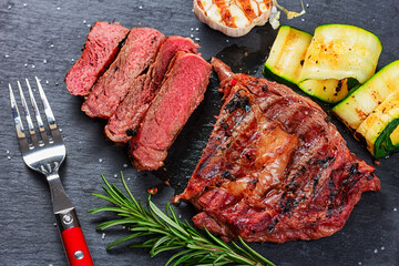 Sticker - Juicy medium rare beef steak slices on ceramic board with herbs spices and salt.