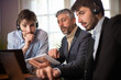© Tof - Photographie - manager ou homme d'affaire d'âge mûr qui travaille au bureau avec deux jeunes employés ou stagiaires. Il donne des conseils. Il est chef d'équipe. Ils travaillent avec des ordinateurs et une tablette