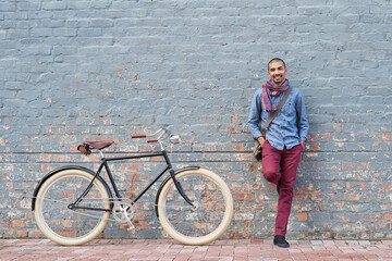 Poster - Why drive when you can cycle. Portrait of a young man posing with his bicycle against a grey wall in the city.