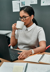 Poster - coffee gets me through it all. shot of a young businesswoman drinking coffee while working on a lapt