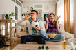© Miljan Živković - two people couple man and woman boyfriend and girlfriend or husband and wife sitting on the sofa at home watching football soccer game cheering copy space celebrate score goal result happy smile