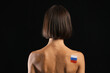 © Pixel-Shot - Beautiful young woman with flag of Russia painted on her body against dark background