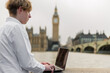 Close up portrait of student with laptop in London  stands on the riverside, London parliament on the background