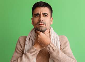 Canvas Print - Ill young man with sore throat on green background