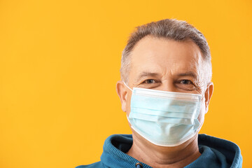Wall Mural - Senior man in medical mask on yellow background, closeup