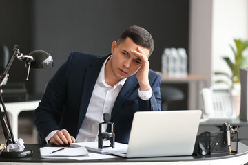 Poster - Worried young businessman sitting at table in office