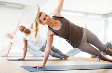 Portrait Of Young Adult Sporty Woman Practicing Yoga With Group At Fitness Center
