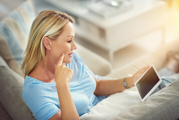 Poster - Timeout with her tablet. Shot of a mature woman relaxing on the sofa with a digital tablet.