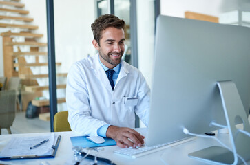 Poster - Staying well-informed about the latest in the medical field. Cropped shot of a young doctor working on a computer in his office.