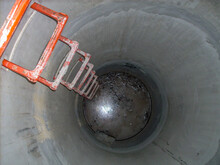 Looking Into An Open Concrete Manhole With Step Rungs Leading Down Stagnant Water