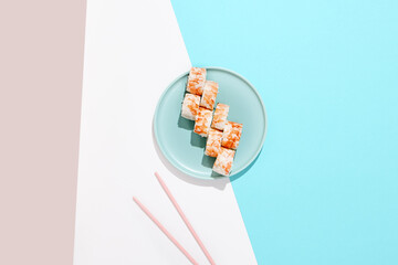 Canvas Print - Maki roll with shrimp on ceramic plate with chopsticks. Shrimp sushi roll with philadelphia cheese on coloured background. Japanese menu concept. Prawn sushi roll in modern style.