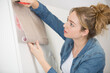 woman sticking adhesive veneer to cupboard