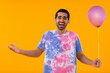 Portrait of happy young man holding balloon and gesturing in front of camera