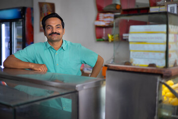 Wall Mural - Portrait of happy Sweet shop owner standing at counter