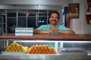 Wall Mural - Sweet shop owner looking at camera with smile while standing at counter
