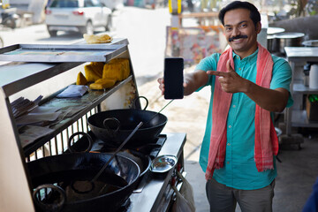 Wall Mural - Street food vendor pointing to his Smartphone for contactless payment