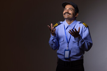 Wall Mural - Indian Security guard wearing a security uniform over isolated dark background gesturing hand and smiling