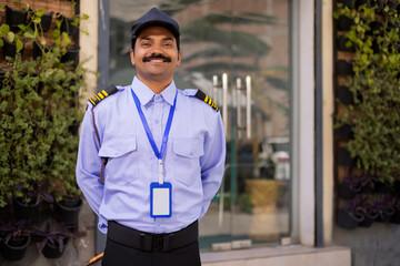 Wall Mural - Portrait of security guard with hands behind back while working at gate