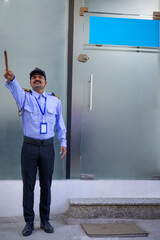 Wall Mural - Security guard pointing away with stick while working in front of gate