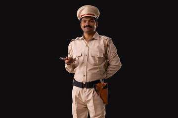 Wall Mural - Portrait of an Indian policeman standing with baton and hand behind back