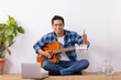 © IndiaPix - Young music teacher showing perfect symbol during online guitar class in living room