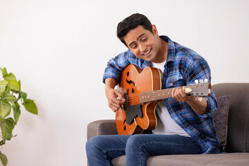 Wall Mural - Portrait of a young musician playing guitar in living room